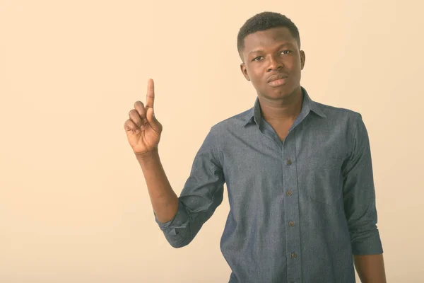 Studio shot of young black African man pointing finger up against white background — Stock Photo, Image