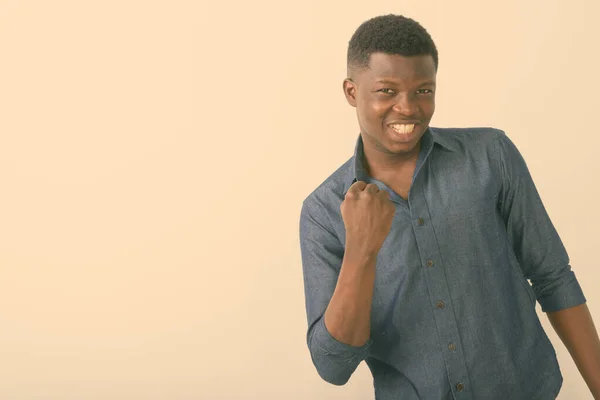 Estudio toma de joven feliz negro africano hombre sonriendo mientras mira motivado contra fondo blanco —  Fotos de Stock