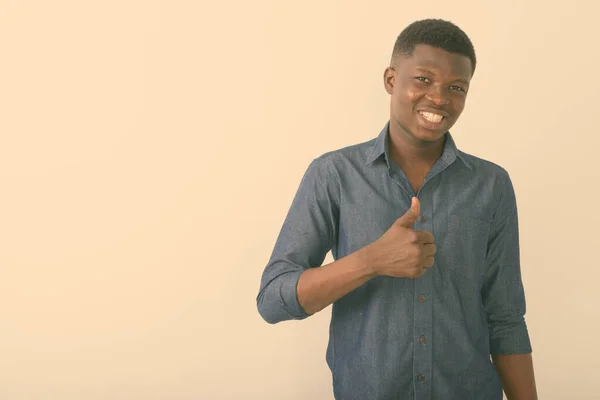 Studio shot of young happy black African man souriant tout en donnant pouce vers le haut sur fond blanc — Photo