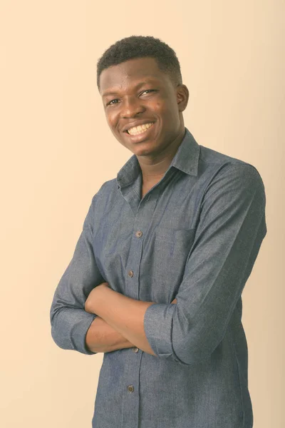 Studio shot of young happy black African man smiling with arms crossed against white background — Stock Photo, Image