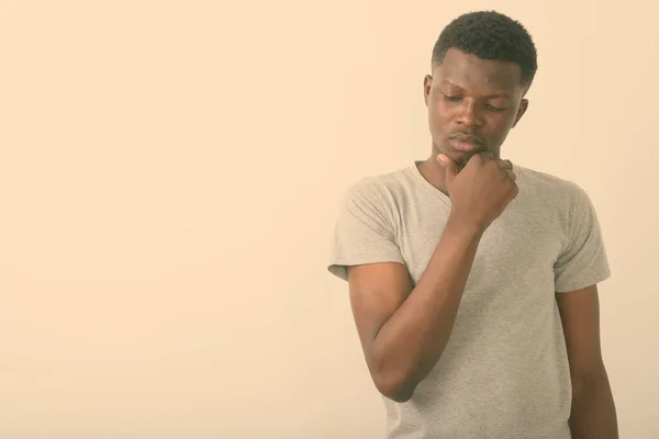 Зйомки молодого африканця, який думає, дивлячись сумно на біле тло — стокове фото