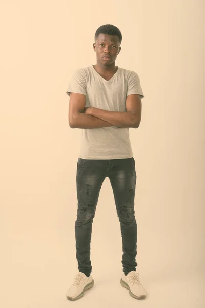 Full body shot of young black African man standing with arms crossed against white background — Stock Photo, Image