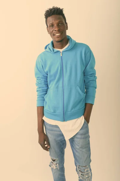 Studio shot van jonge gelukkig zwart Afrikaanse man glimlachen en staan met de hand in zak tegen een witte achtergrond — Stockfoto