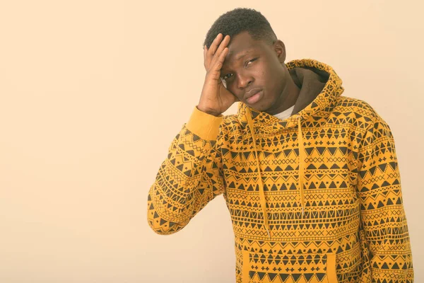 Studio shot of young black African man having headache against white background — Stock Photo, Image