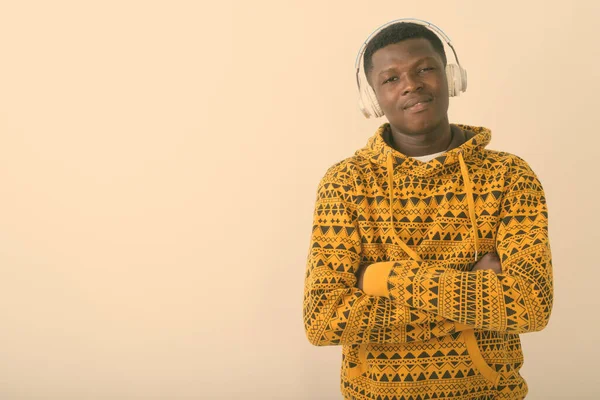 Estúdio tiro de jovem negro africano ouvindo música com braços cruzados contra fundo branco — Fotografia de Stock