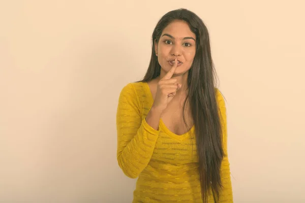 Estúdio tiro da jovem mulher indiana com o dedo nos lábios contra o fundo branco — Fotografia de Stock