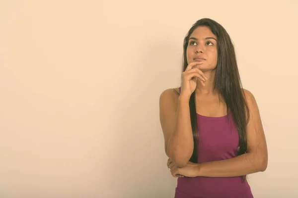 Captura de estudio de la joven mujer india pensando mientras mira hacia arriba sobre fondo blanco —  Fotos de Stock