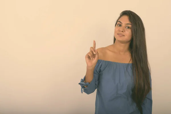 Studio colpo di giovane donna indiana puntando il dito contro sfondo bianco — Foto Stock