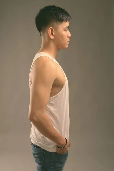 Asyalı yakışıklı genç adam gri arka planda kolsuz bluz giyiyor. — Stok fotoğraf