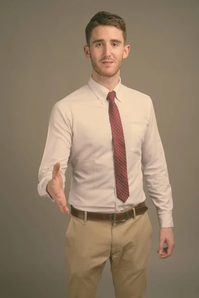 Young handsome businessman against gray background — Stock Photo, Image