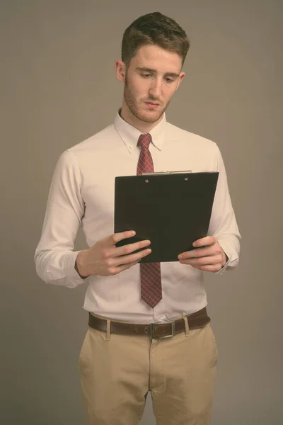 Joven hombre de negocios guapo contra fondo gris — Foto de Stock