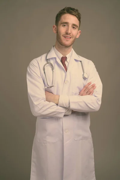 젊고 잘생긴 남자, 회색 배경에 대항하는 의사 — 스톡 사진