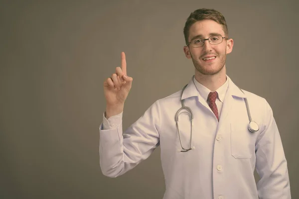 若いですハンサムな男医師身に着けています眼鏡でグレー背景 — ストック写真