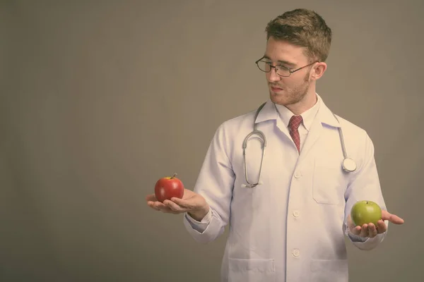 Молодой красивый доктор в очках на сером фоне — стоковое фото