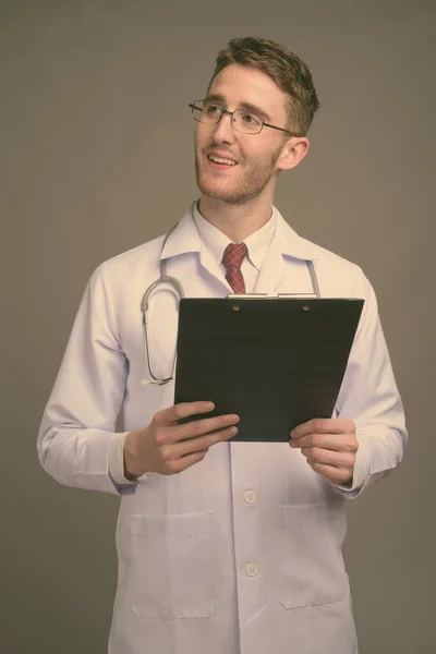 Jeune homme beau médecin portant des lunettes sur fond gris — Photo