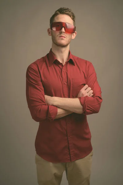 Mladý pohledný podnikatel v červené košili na šedém pozadí — Stock fotografie