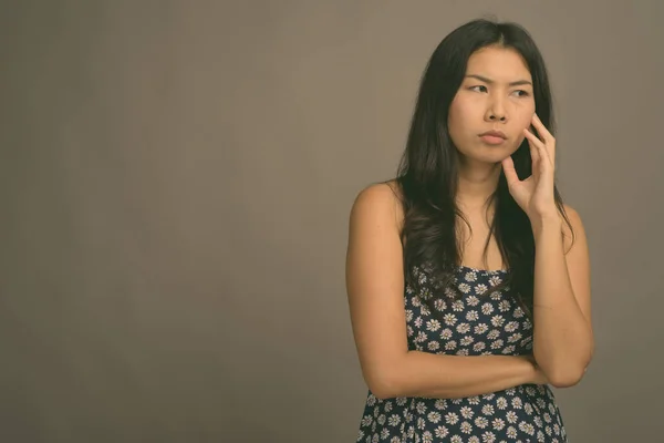 Aziatische vrouw het dragen van blauw jurk tegen grijs achtergrond — Stockfoto