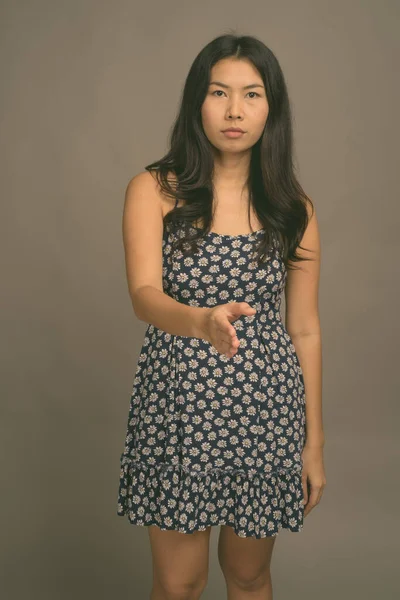 Mujer asiática vistiendo vestido azul contra fondo gris —  Fotos de Stock