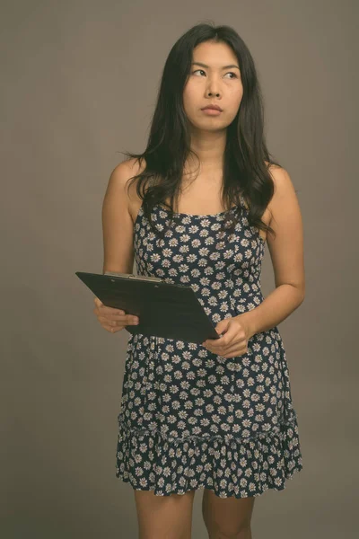 Mujer asiática vistiendo vestido azul contra fondo gris — Foto de Stock