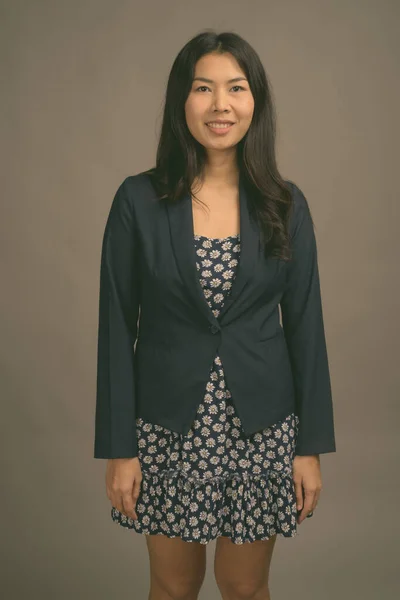 Mulher asiática vestindo vestido azul e camisola cardigan contra fundo cinza — Fotografia de Stock