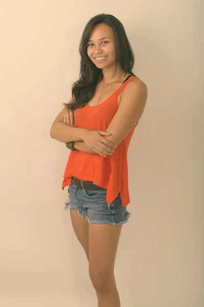 Estudio de la joven mujer asiática feliz sonriendo y de pie con los brazos cruzados sobre fondo blanco — Foto de Stock