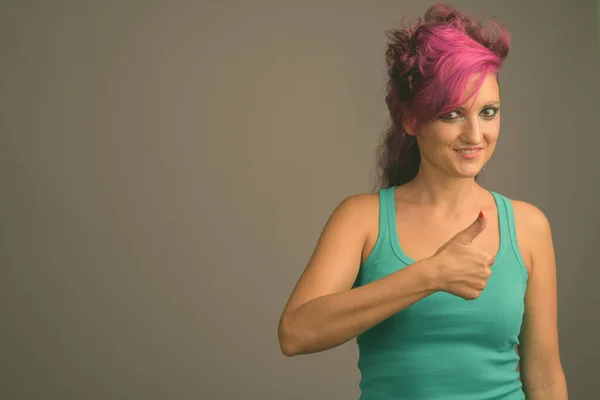 Bella donna con i capelli rosa e make-up contro sfondo grigio — Foto Stock