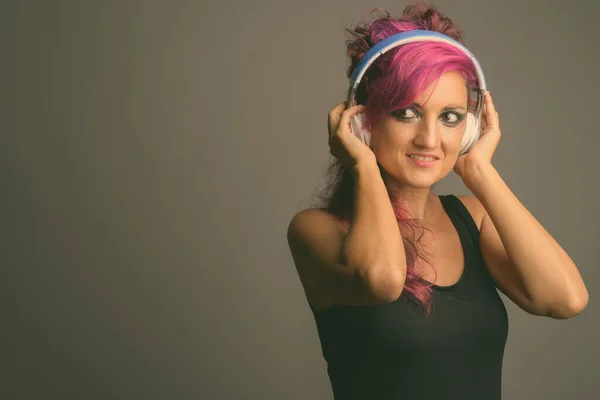Bella donna con i capelli rosa e make-up contro sfondo grigio — Foto Stock