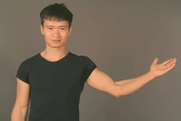 Студийный снимок молодого китайца на сером фоне — стоковое фото