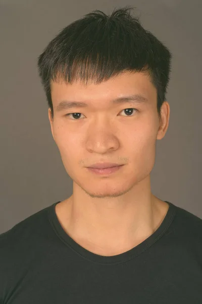 Studio skott av ung kinesisk man mot grå bakgrund — Stockfoto