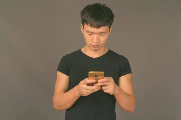 Studioaufnahme eines jungen Chinesen vor grauem Hintergrund — Stockfoto