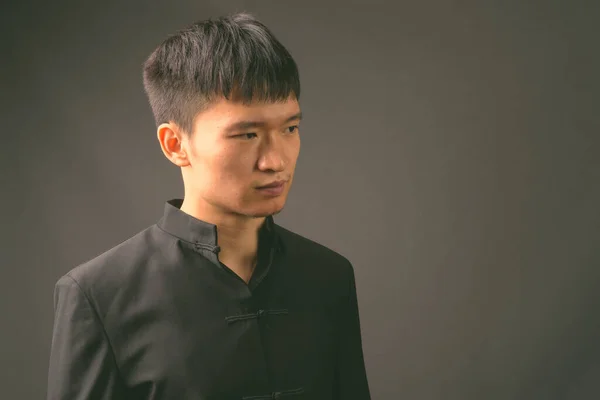 Siyah beyaz giymiş genç Çinli adamın stüdyo fotoğrafı. — Stok fotoğraf
