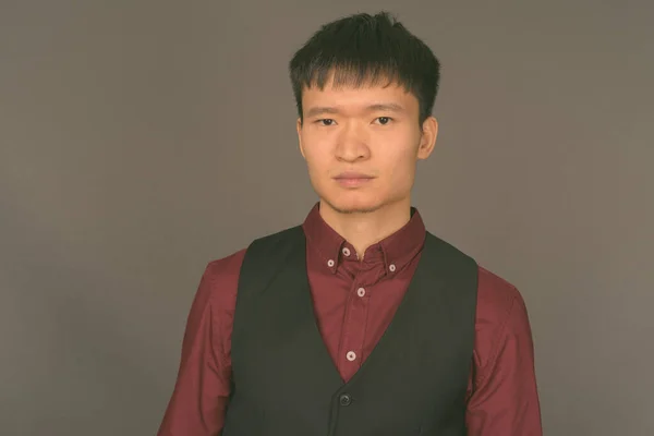 Junger chinesischer Geschäftsmann vor grauem Hintergrund — Stockfoto