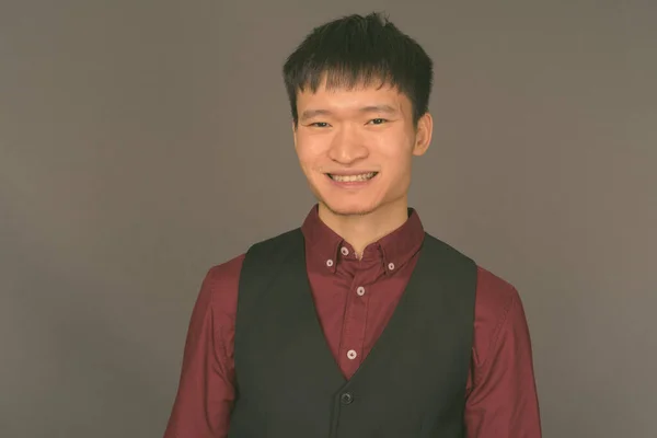Ung kinesisk affärsman mot grå bakgrund — Stockfoto