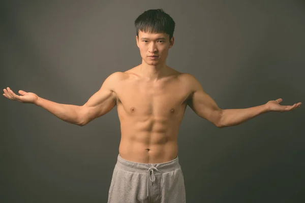 셔츠를 입지 않고 회색 배경을 반대하는 중국인 청년 — 스톡 사진