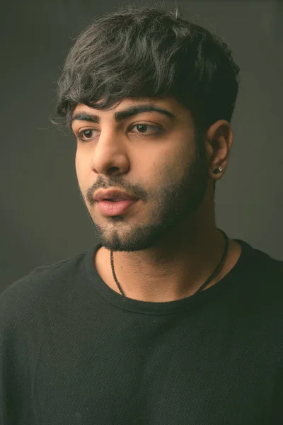 Junger gutaussehender indischer Mann vor grauem Hintergrund — Stockfoto