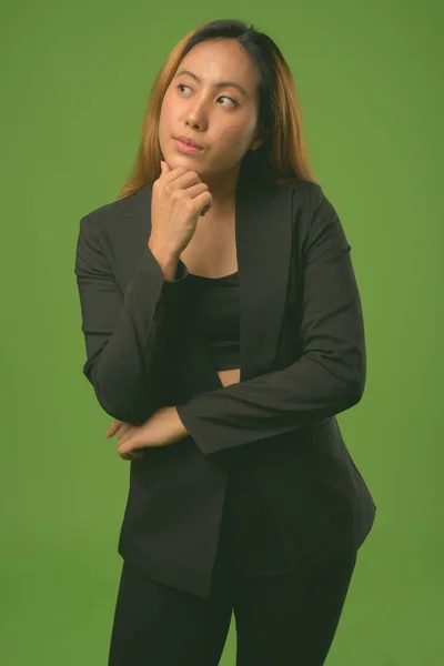Porträtt av ung asiatisk affärskvinna mot grön bakgrund — Stockfoto
