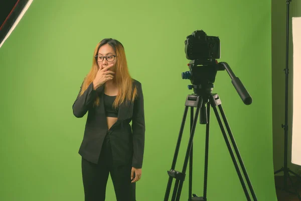 Jovem empresária asiática vlogging contra fundo verde — Fotografia de Stock