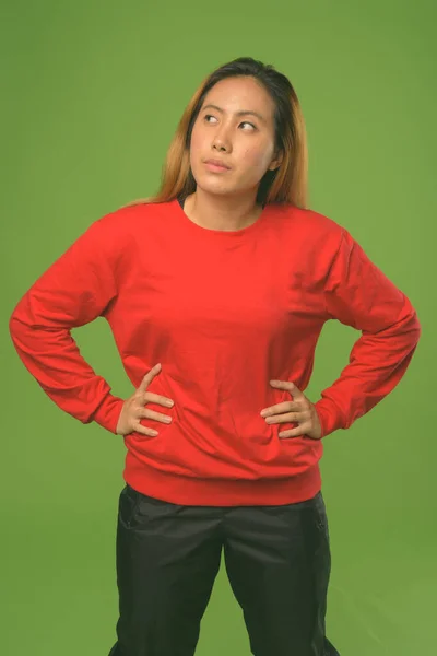 Joven mujer asiática vistiendo camisa roja sobre fondo verde —  Fotos de Stock