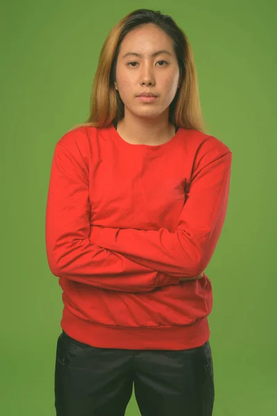 Giovane donna asiatica indossa camicia rossa contro sfondo verde — Foto Stock