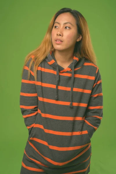 Joven mujer asiática usando sudadera con capucha contra fondo verde —  Fotos de Stock