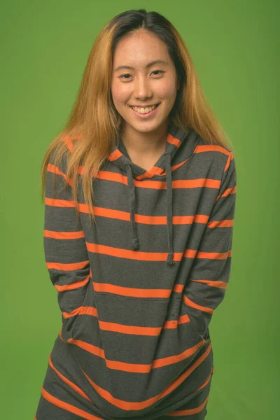 Jovem mulher asiática usando capuz contra fundo verde — Fotografia de Stock