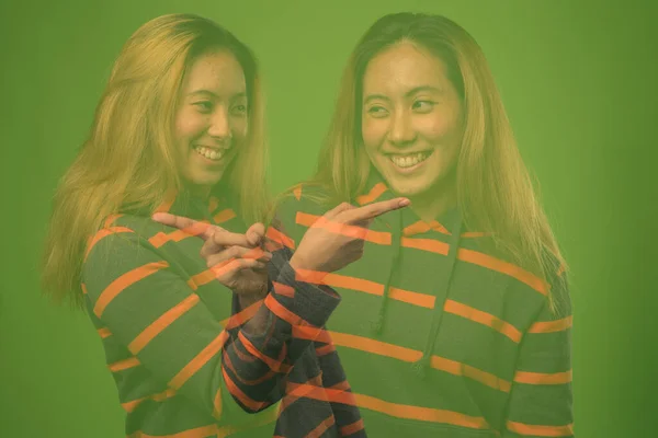 Doppelbelichtungsschuss einer jungen Asiatin vor grünem Hintergrund — Stockfoto