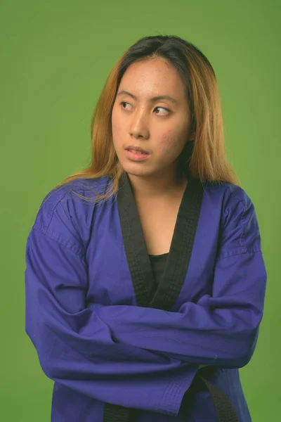 Joven mujer asiática usando karate azul Gi contra fondo verde —  Fotos de Stock