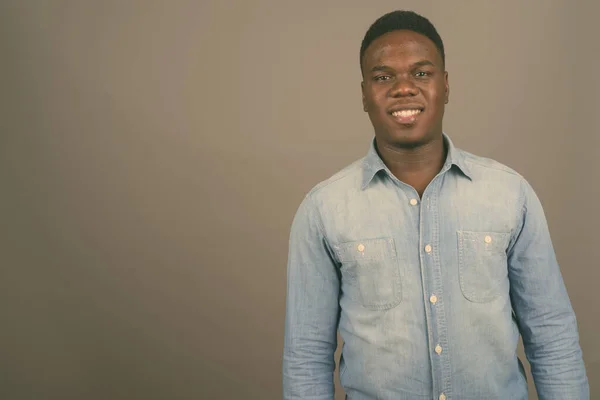 Jovem africano vestindo camisa jeans contra fundo cinza — Fotografia de Stock