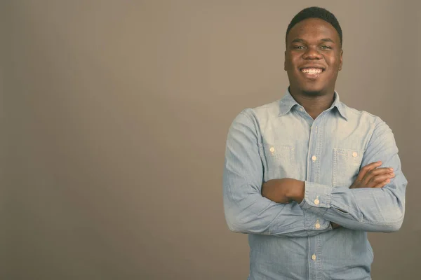 Jovem africano vestindo camisa jeans contra fundo cinza — Fotografia de Stock