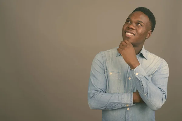 Jovem africano vestindo camisa jeans contra fundo cinza — Fotografia de Stock