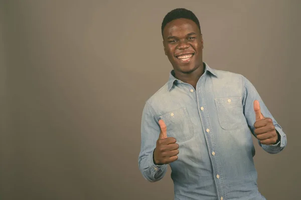 Joven hombre africano con camisa de mezclilla sobre fondo gris —  Fotos de Stock