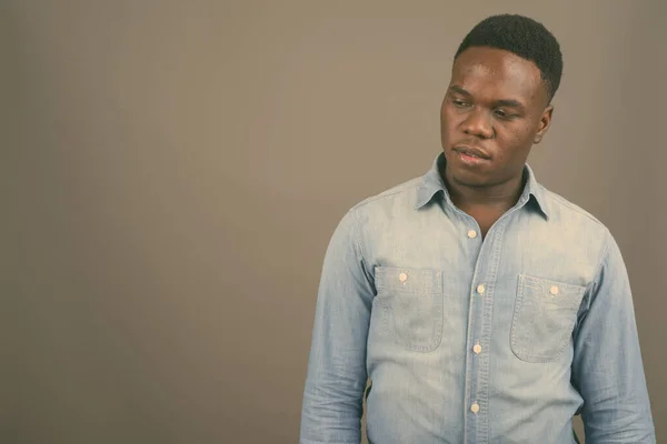 Jovem africano vestindo camisa jeans contra fundo cinza — Fotografia de Stock