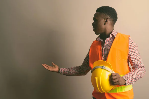Joven trabajador de la construcción africano mostrando algo en blanco y negro —  Fotos de Stock