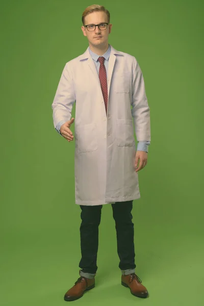 Jovem médico homem bonito com cabelo loiro contra fundo verde — Fotografia de Stock